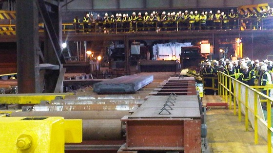 Workers look on as the first piece of steel is produced
