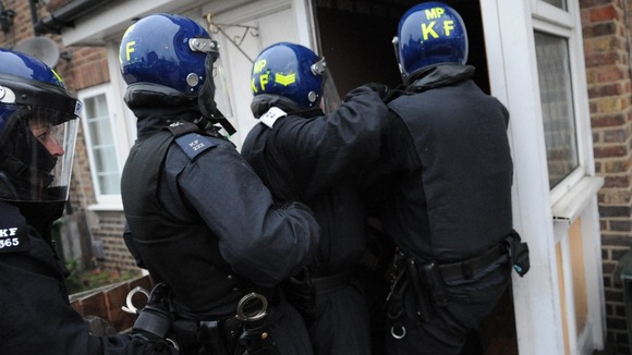 Police officers enter a house as part of a crackdown on gang crime