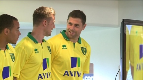 Norwich City captain Grant Holt shows off the club's new home strip with teammates