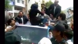 A women sits on Iranian President Ahmadinejad's vehicle to tell him about her economic conditions