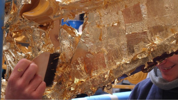 Craftsmen apply gold leaf.