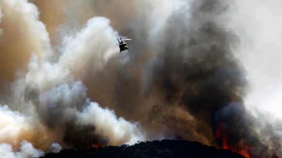 A water-dropping helicopter makes a drop on a fast moving bush fire