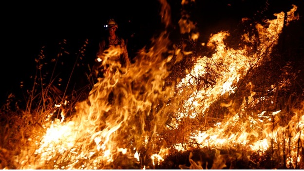 A firefighter with the Silver City Hotshots uses a drip torch to start a back fire.