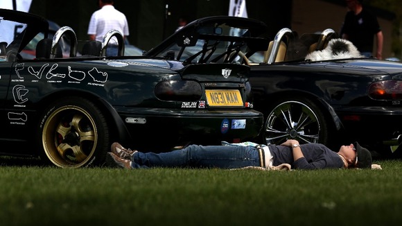 A woman relaxes in the sun at a car show held at Imperial War Museum Duxford in Cambridgeshire