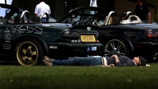 A woman relaxes in the sun at a car show held at Imperial War Museum Duxford in Cambridgeshire