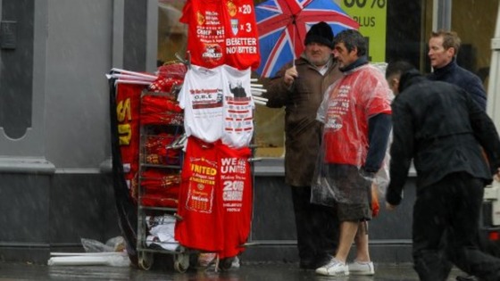 A stall holder sells Manchester United related Merchandise as rain pours down