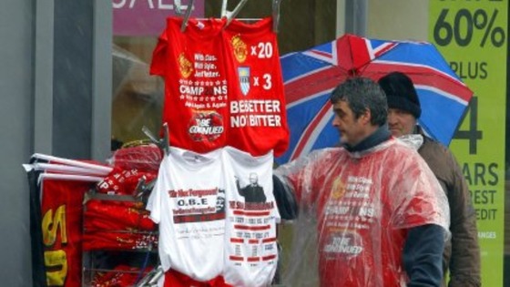 A stall holder sells Manchester United related Merchandise as rain pours down ahead of the Premier League winners parade through Manchester.
