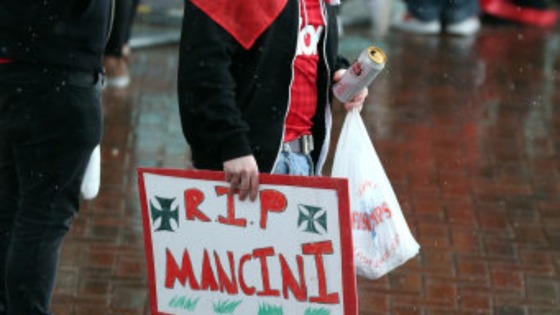 A Manchester United fan with a banner taunting rivals Manchester City ahead of the parade through Manchester. 