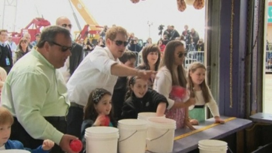 Prince Harry flings a coloured ball at a target in an amusement arcade at Jersey Shore