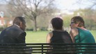 Man on park bench chats to 2 women seen from behind