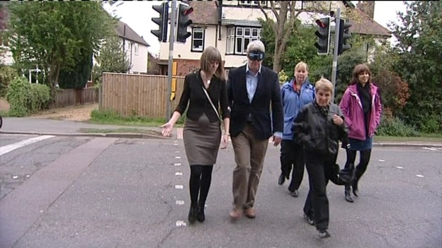 Andrew Lansley wearing blindfold walking across crossing