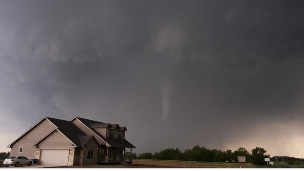 A tornado is pictured near a home