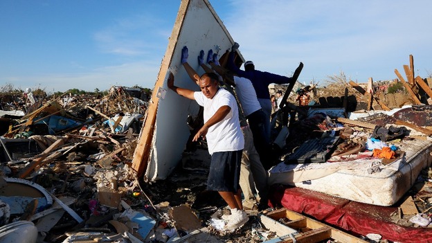 Men lift a wall in an effort to salvage belongings from their tornado-ravaged homes in Moore.