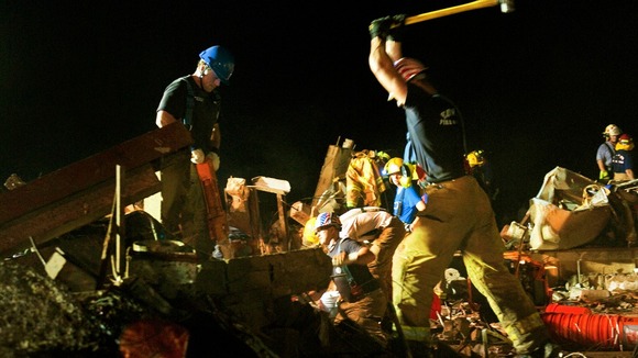 Two firefighters break through concrete during the search for survivors in the remains of the Plaza Towers Elementary School.