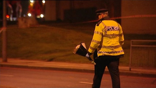Police move a bouquet of flowers as tribute continued to arrive through the night.