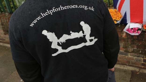 Men wearing Help For Heroes clothing leave flowers at the scene