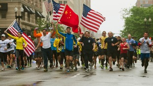 Runners carry American and Chinese flags as they approach the finishing line.