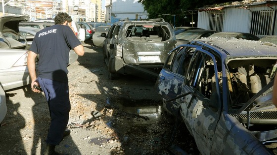 A policeman inspects damaged cars after two rockets hit houses and parked cars in Beirut 