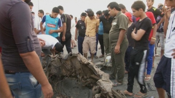 Baghdad residents inspect a piece of twisted metal close to one of the blasts