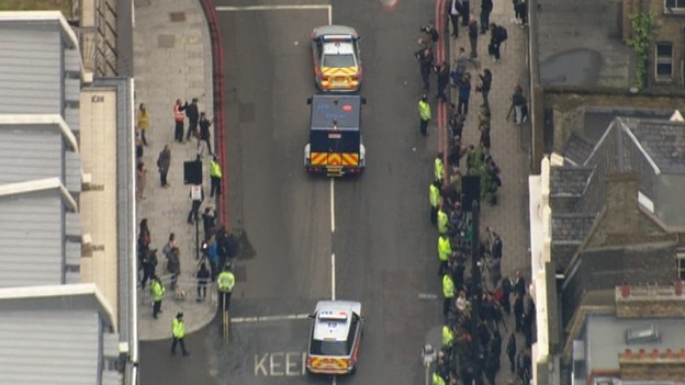 Two police cars escort the prison van from the court
