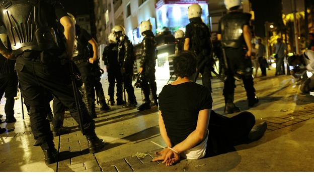 A demonstrator sits on the ground after he was detained by riot police 