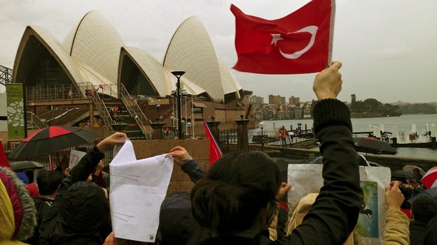 Turkish protesters hold banners and Turkish national flags on the steps of the Sydney Opera House.