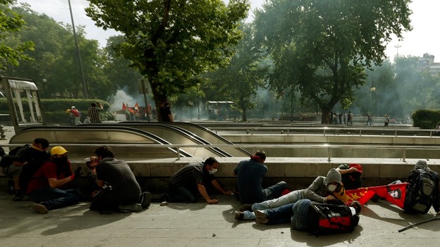 Protesters take cover as Turkish riot police use tear gas in central Ankara.