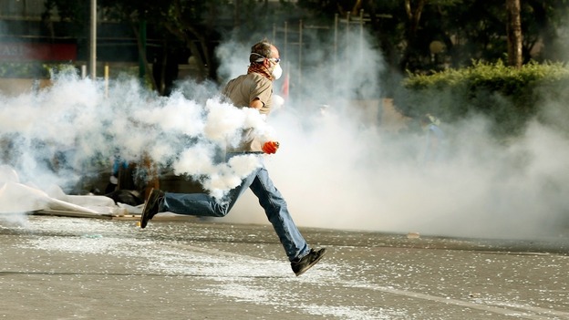 A demonstrator runs as he throws a tear gas canister back at riot police in Turkey's central Ankara.