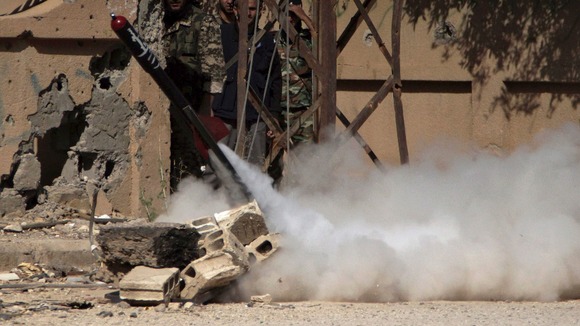Free Syrian Army fighters react during the firing of a rocket.