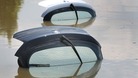 Open boots of two cars stick out of the water