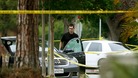 A police officer is seen by a bullet riddled car