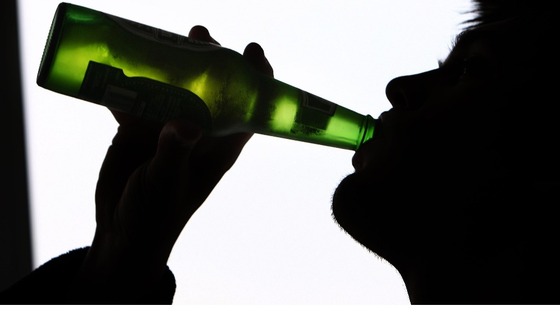 A man swigs from beer bottle