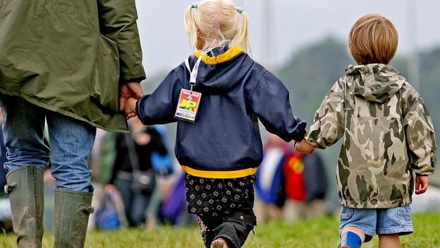 A man walks hand in hand with two children.