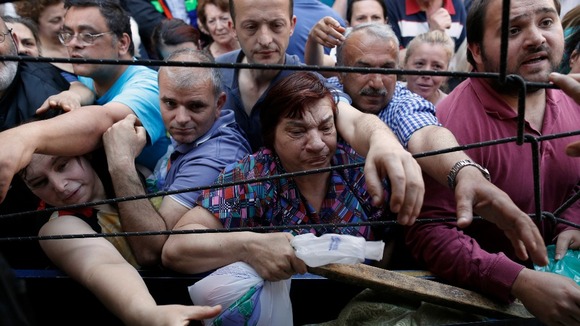 People reach out to grab free fruit and vegetables last month in Athens.
