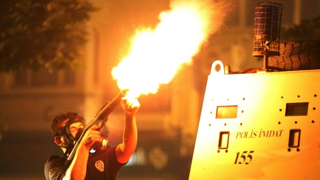 A police officer fires tear gas towards protesters in Istanbul.