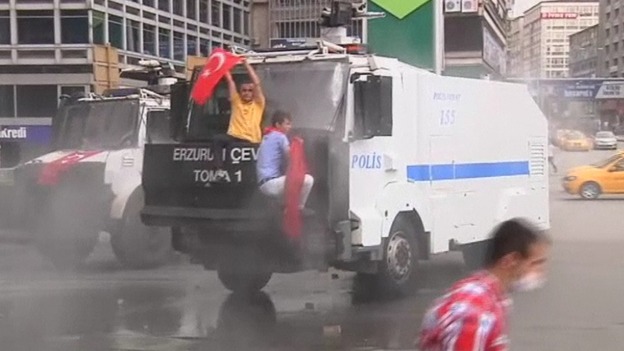 A protester waves a Turkish flag in front of the windscreen