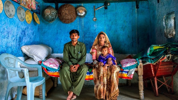 Shugna, holding their daughter Kawila, and Marjee sit in their house in Umerkot District, Sindh province, Pakistan, April 10, 2013.