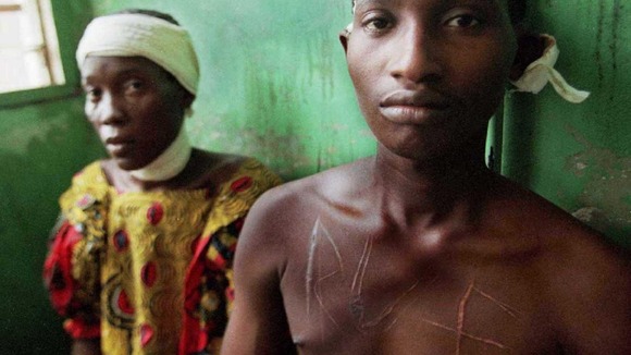 Members of the RUF hold a young man down in Sierra Leone.