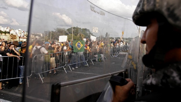 Riot police shield themselves from protesters.