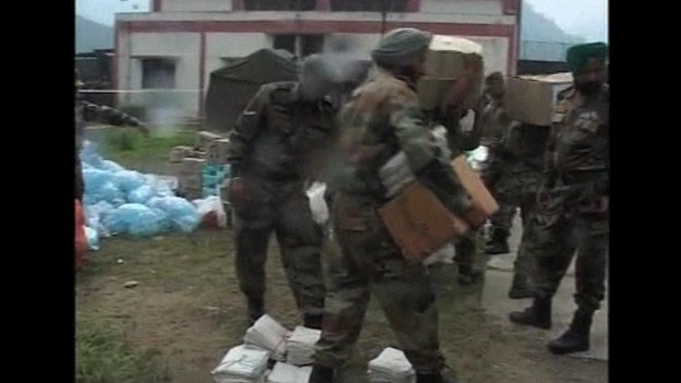 Members of the Indian armed forces help carry supplies to flood victims
