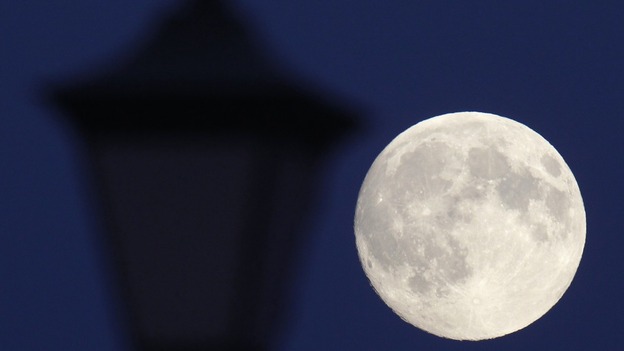 The moon rises behind a street lamp in St Petersburg