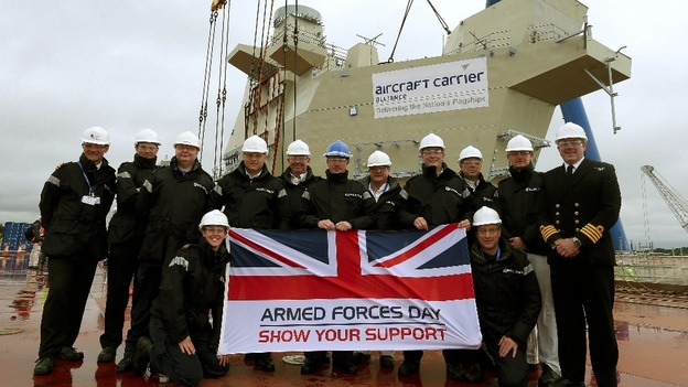 Navy personnel with an Armed Forces Day Flag