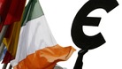 An Irish flag flies next to a symbol of the euro currency at the entrance of the European Parliament in Brussels.