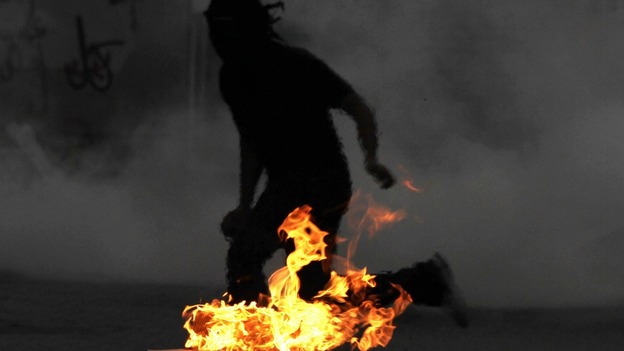 A Bahraini anti-government protester runs from tear gas fired by riot police.