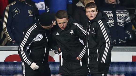 The ball boy who was kicked by Chelsea's Eden Hazard is helped off the pitch.