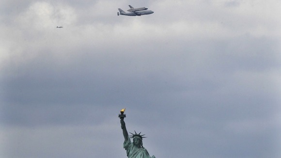 Space shuttle Enterprise sits on top of a NASA Shuttle Carrier Aircraft above the Statue of Liberty in New York.