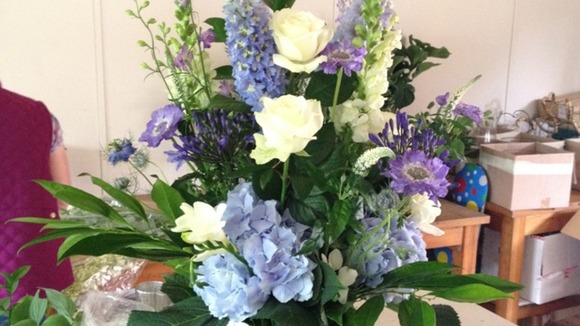 Theflowers are blue and cream and consist of foxglove, freesia and hydrangea.