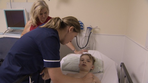 Nurse tends to young boy lying on hospital bed