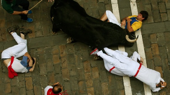 A runner holds the horn of an El Pilar fighting bull during the sixth bull run in Pamplona.