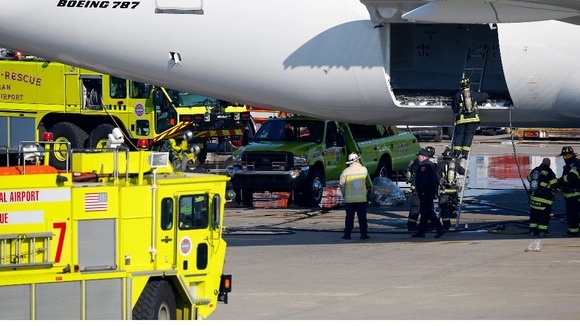 Firefighters climb into a rear cargo compartment of a Japan Airlines Boeing 787 Dreamliner.